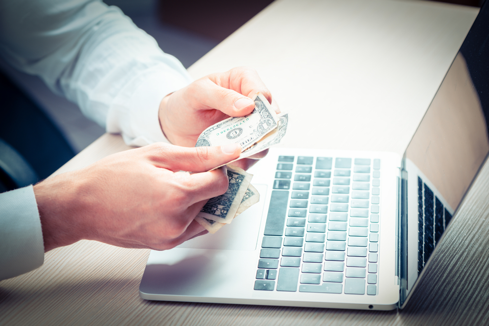 Homme devant son ordinateur comptant ses économies liées au service informatique